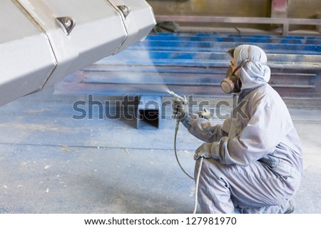 vehicle painter spraying white color on construction bucket