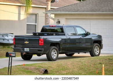 Vehicle Parked In Front Of Wide Garage Double Door On Paved Driveway Of Typical Contemporary American Home. Tampa, Florida, USA - June 3, 2022.