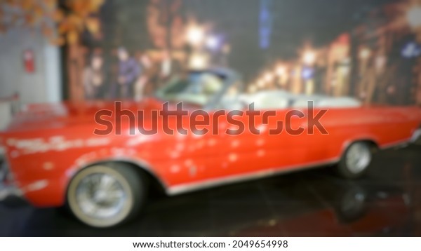 Vehicle purchase, rental, lease\
concept. Blurred view of automobile dealership store interior with\
new modern cars, copy space. Defocus of Historic antique\
car