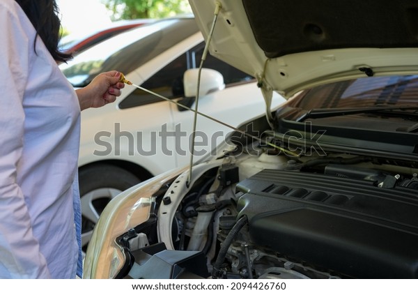 Vehicle safety\
concept, Woman\'s hand checking car engine before driving. Car\
Maintenance engine oil level\
checking.