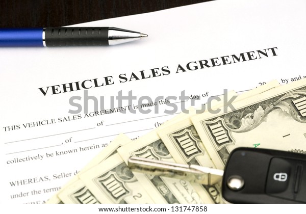 Vehicle sales agreement document contract with car
key and pen