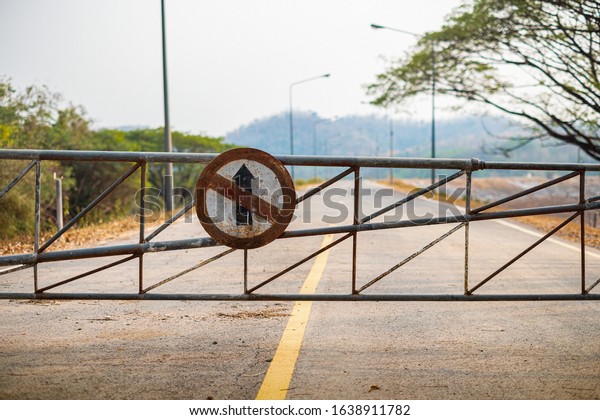 Vehicle Security barrier Gate and Do not\
go straight direction old traffic sign on the\
road