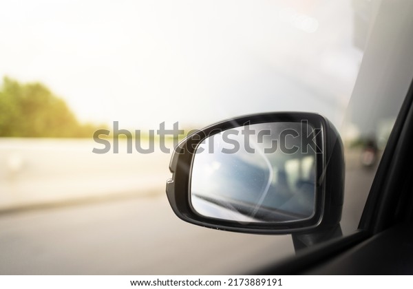 Vehicle side mirror while vehicle\
moving on the highway with copyspace. Safety driving\
concept.