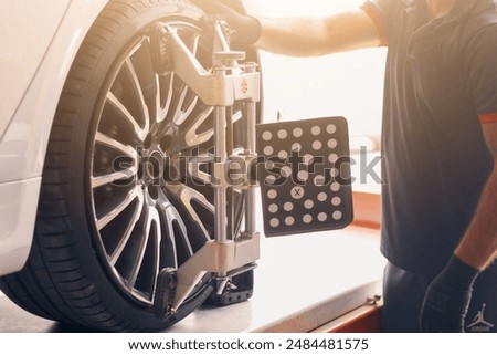 Vehicle wheel alignment. Tyre wheel alignment. Technician placing sensors to tires for Alignment.Electronic Wheel Balance. Caster Camber Adjustment.