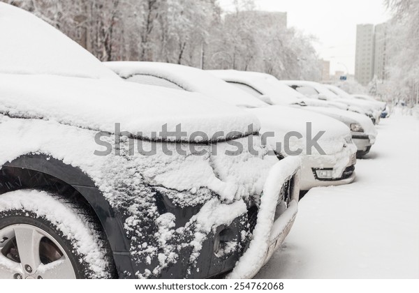  vehicles covered with snow in the winter blizzard in\
the parking lot