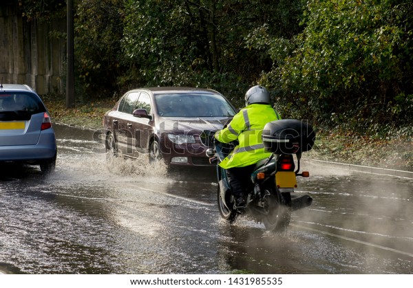 Vehicles\
drive through flood water on a road in\
England