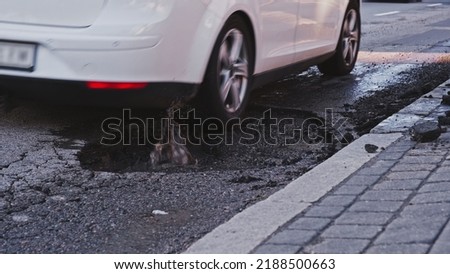 Vehicles Driving Over Deep Large Erosion Hole in City Street Asphalt after Severe Weather and Heavy Rainfall Risking of Damage to Car Tyre and Suspension	