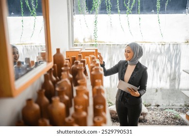 veiled businesswoman carrying a tablet working to put crafts on the shelf - Powered by Shutterstock