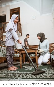 Veiled Girl Using Vacuum With Family Cleaning The House Together