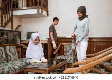 Veiled Mother Using Vacuum With Family Cleaning The House Together