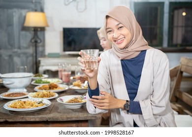 A Veiled Woman Smiles At The Camera Holding A Glass To Break The Fast Together In The Dining Room