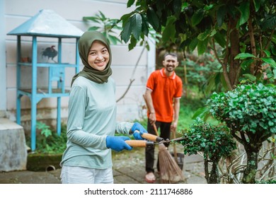 Veiled Woman Uses Plant Shears To Trim Ornamental Plant Leaves