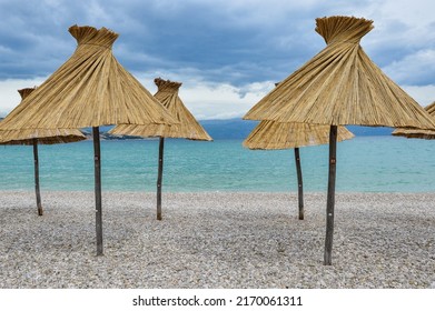 Vela plaza pebble beach with bamboo parasols at Baska, Krk island.