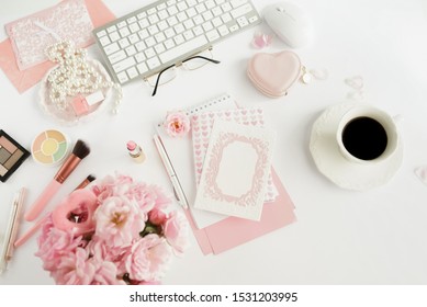 Velentine's day concept.Feminine desk workspace with laptop, bouquet of pink roses, glasses,cup of coffee, makeup cosmetics, card mock up on white background. Flat lay, top view .Copy space