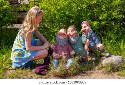 Veliky Novgorod, Russia. 17.06.12. Girl Sitting Next To The Figures Of Dwarves In The Park