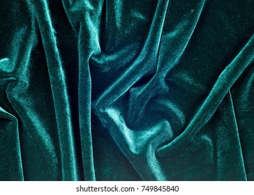 velor fabric texture, background, green. Velvet velor cloth background with glowing light and dark shadows. Background for theater and fashion design themes.
