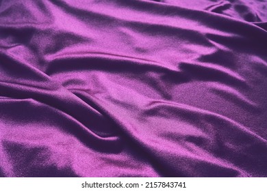 Velour fabric, similar to silk. Textiles in a folds and beautiful waves. Purple, pink, magenta shades on the drapery. Sewing material for evening dresses, furniture upholstery, curtains and interior