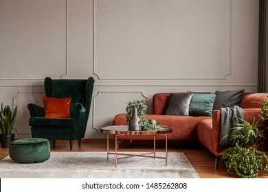 Velvet emerald green armchair with orange pillow next to corner sofa and coffee table