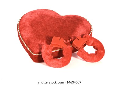 A Velvet Heart Shaped Box Filled With Valentine's Day Candy (chocolate?) With Fuzzy Handcuffs. Isolated On White.