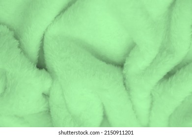 Velvet. Plush. Pale Green. (from the French peluche) - textiles with a short pile or nap, the same as fustian or velvet. Green animal fur texture background, plush furry fur close-up texture.