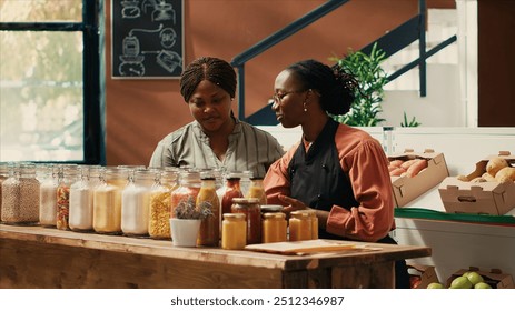 Vendor presenting additives free bulk items for client in store, recommending types of vegan organic pasta in recyclable jars. Merchant with apron showing pantry essentials to buyer, eco friendly. - Powered by Shutterstock