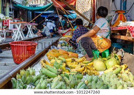Vendors at famous Maeklong railway market selling fruit and vegetables at railway tracks, Samut Songkhram province, Thailand