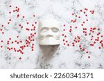 Venetian Bauta mask, Casanova mask on a marble background with confetti hearts. Concept - Venetian carnival masquerade, festival, travel, holiday. Flat lay. Close-up. Copy space.