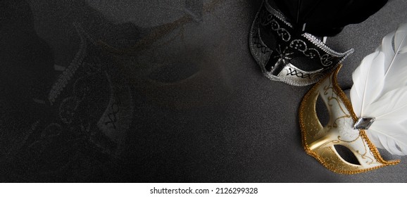 Venetian black, gold and white masks on dark silver glitter background. New year, Christmas, Purim, Mardi Gras party celebration design banner. Carnival masquerade costume ball