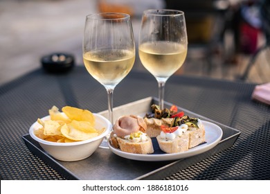 Venetian Cicchetti snacks and two glasses of white wine in a snack bar in Venice, Italy - Shutterstock ID 1886181016