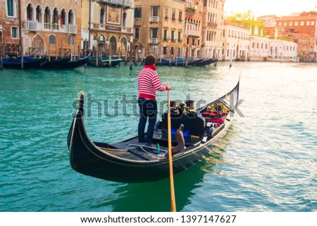 Venetian gondolier carries tourists on gondola Grand Canal of Venice, Italy