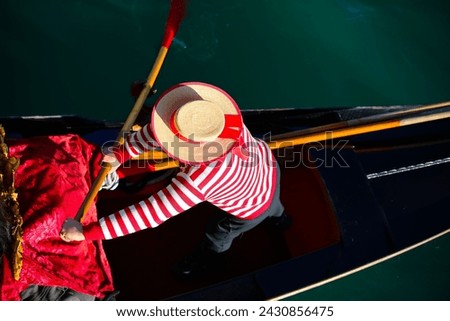 Venetian gondolier with hat and typical white and red dress while rowing on the gondola on the grand canal in Venice in Italy in Europe