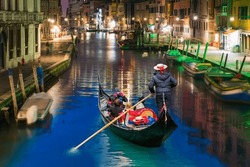 Venetian Gondolier Punting Gondola Through Green Canal Waters At Night - Venice Italy