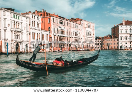 Venetian gondolier punting gondola through grand canal of Venice, Italy. Gondola is a traditional, flat-bottomed Venetian rowing boat. It is the unique transportation of Venice, Italy.