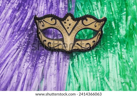 Venetian Mask. Costume for carnival ball and parties. Background of green and purple plastic strips.