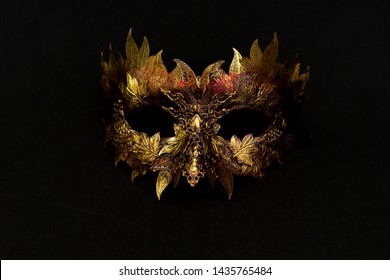 Venetian mask in gold and red with metallic pieces in the form of leaves. original and unique design, handmade crafts