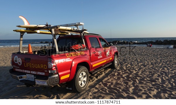 Venice Beach, CA / USA -\
June 16, 2018: A vivid red Toyota Tacoma off road truck serving as\
life guard vehicle is parked on Venice Beach at sunset             \
          