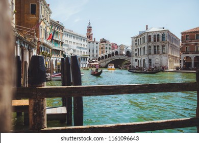 Venice Channel With Gandols With Tourists And Gondoliers Around The Beautiful Architecture Of A Sinking City