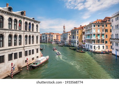 Venice, Italy, 07.04.2019: landscaping view from Rialto Bridge to Grand Canal, boat taxi station and old houses along the canal.