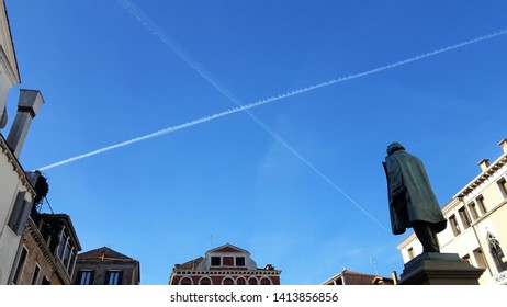 Venice, Italy - 20th November 2017: A cross of X in the sky from aeroplane trails with the Vancian Buildings and statues framing the picture. Space for copy text. Background. Smoke trails.