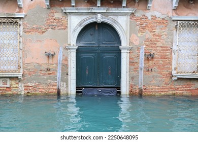 Venice, Italy flooded by high tide: Old weathered brick facade and damaged gate at a canal in quarter Cannaregio - Powered by Shutterstock