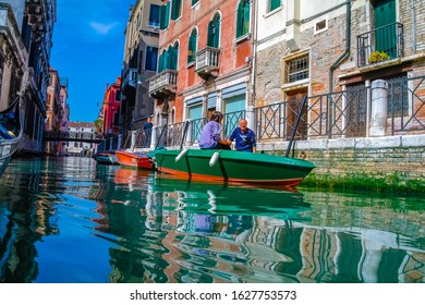 VENICE, ITALY - JANUARY 16, 2020: Gondolas and boats sailing on Venice canals, with tourists and gondoliers with famous Venetian monuments and architecture. Romantic and beautiful city of Venice.
