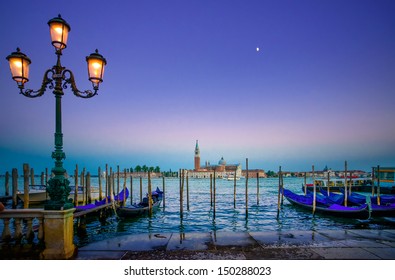 Venice, street lamp and gondolas or gondole on a blue sunset twilight and San Giorgio Maggiore church landmark on background. Italy, Europe.