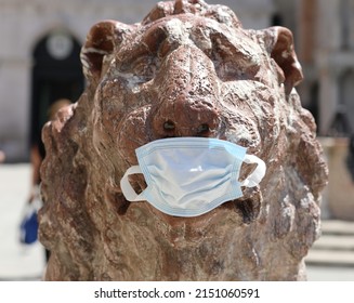 Venice, VE, Italy - July 13, 2020:
 Detail of Statue of Lion in Marble with surgical mask during italian lockdown