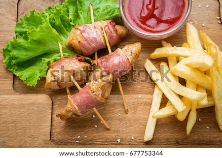 Venison kebab and rasher of crispy bacon. Wooden background
