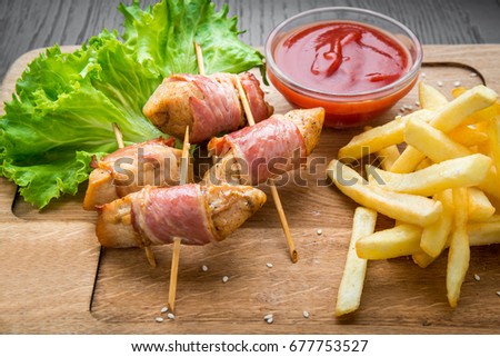 Venison kebab and rasher of crispy bacon. Wooden background