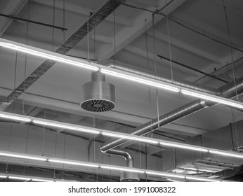 Ventilation and air conditioning system in industrial or commercial premises with lighting, under the ceiling. Ventilation pipes and hoods. Monochrome black and white image.