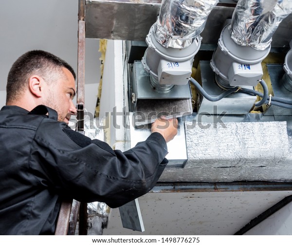Ventilation cleaning. Specialist at\
work. Repair ventilation system (HVAC). Industrial\
background