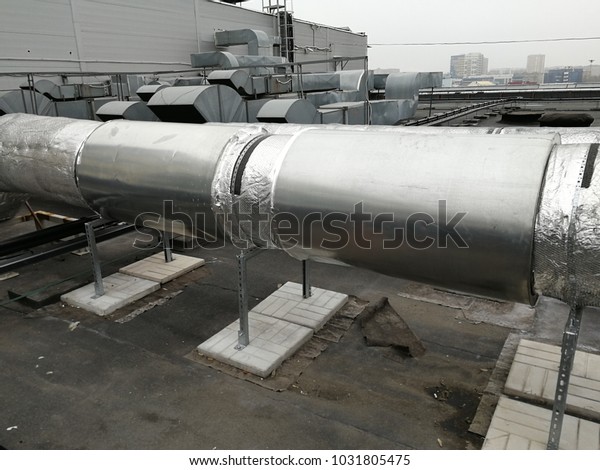 Ventilation exhausting\
fan with exhaust vented ventilation pipes standing on the roof of\
the business\
center.