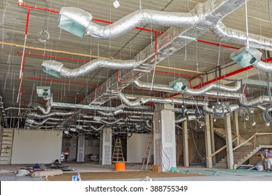 Ventilation pipes in silver insulation material hanging from the ceiling inside new building 