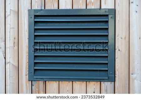 Ventilation shaft with a metal cover on a wooden wall